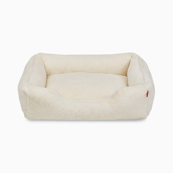 Sammy bolster dog bed in a medium white faux fur by Fuzi, with a removable cover available in four beautiful colors and three sizes.