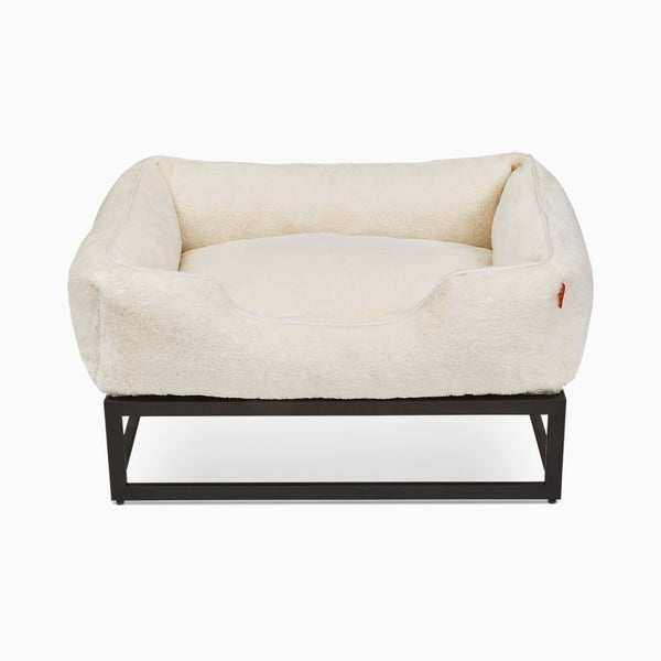 The Fuzi Elevated Dog bed in white faux fur, raised luxury dog beds by Fuzi, designed for enhanced airflow, support, and comfort, in white plush with a black metal base.