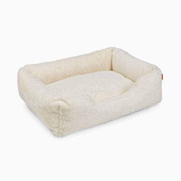 The Sammy bolster dog bed in a medium white faux fur by Fuzi, with a removable cover available in four beautiful colors and three sizes.